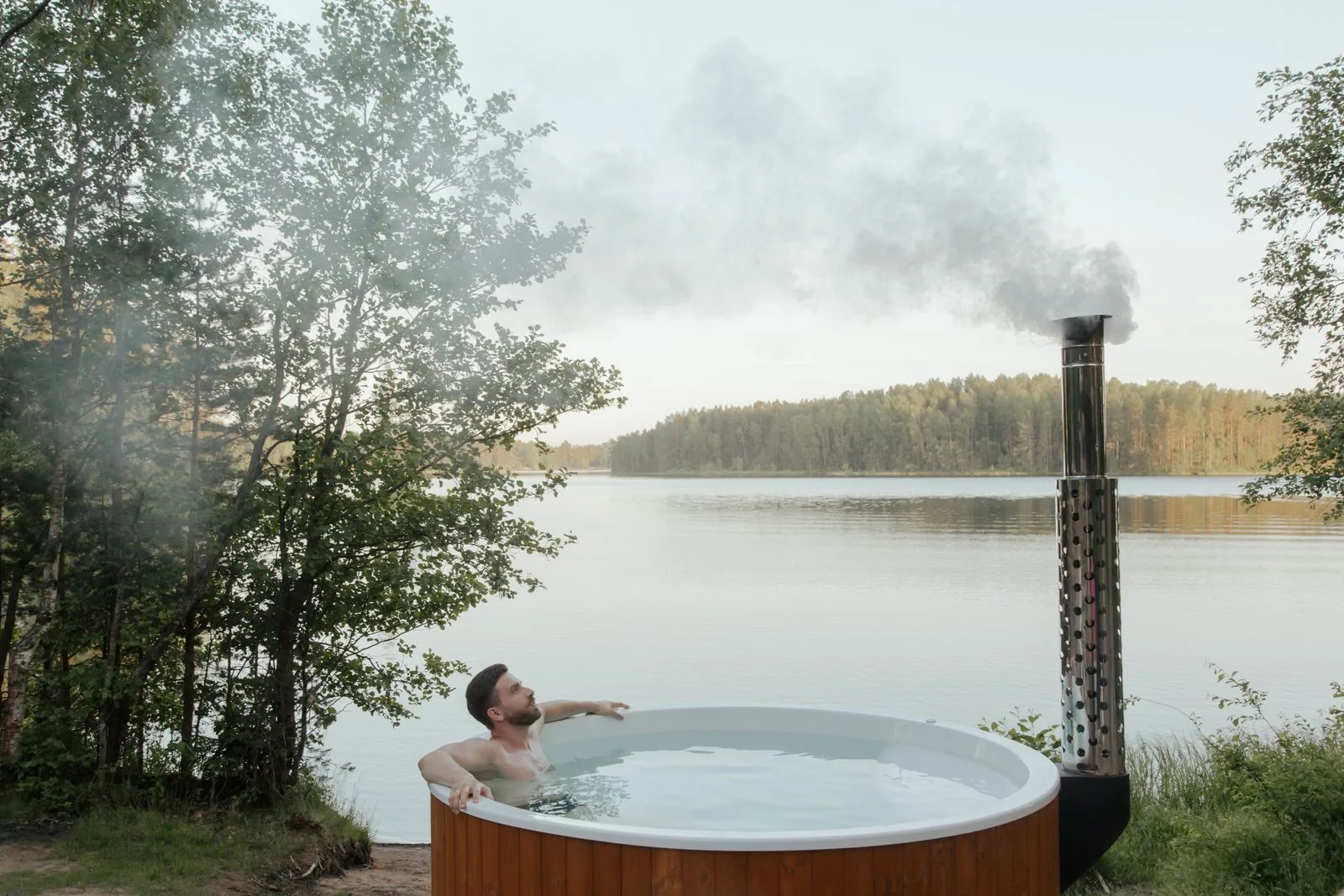 Couple relaxing in an outdoor inflatable hot tub beside a lake