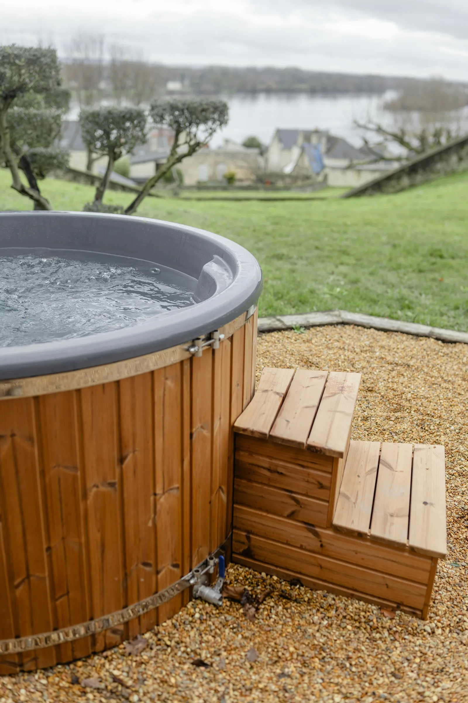 Outdoor hot tub on a gravel pad, the kind of setup where a cover lifter needs space behind the spa