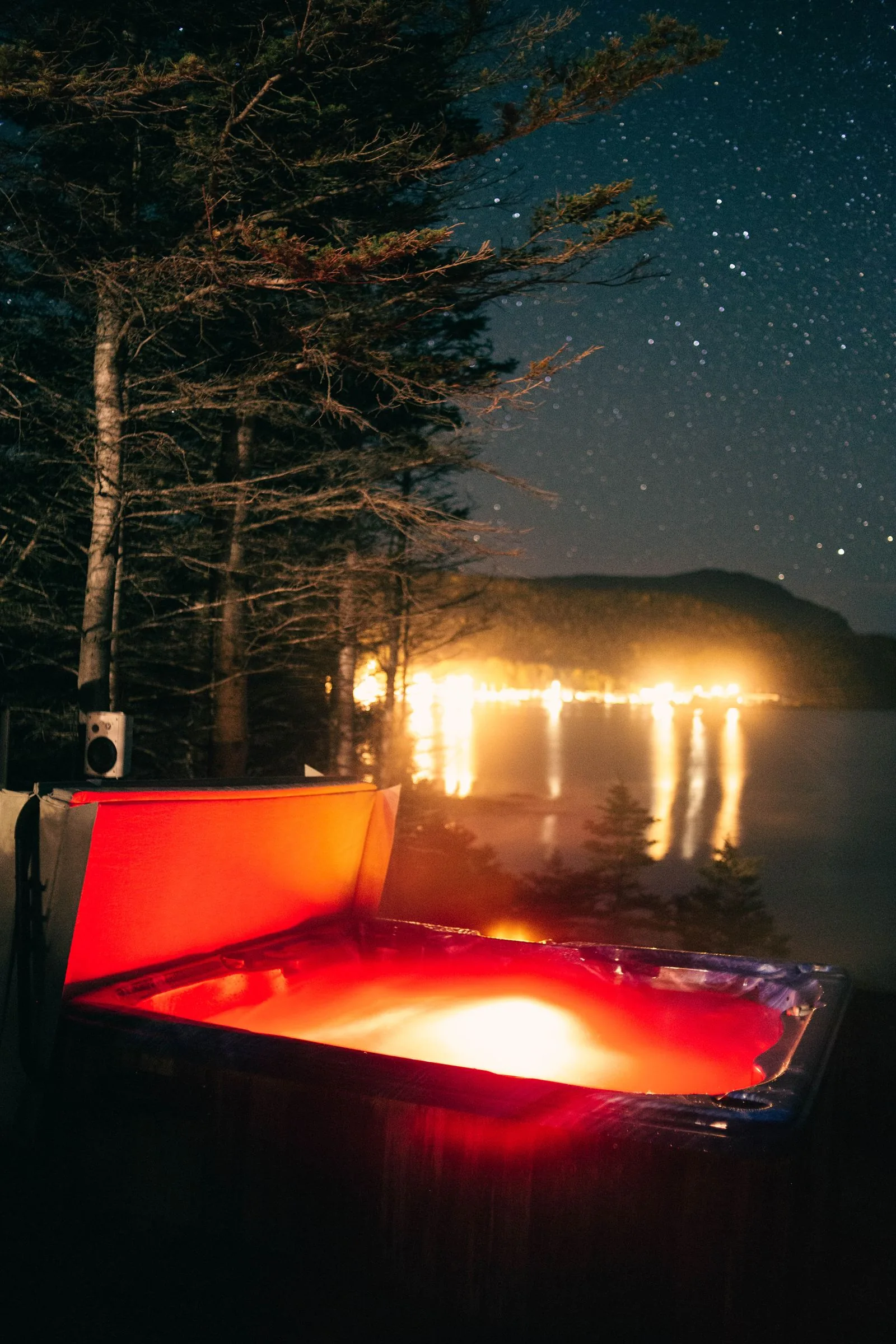 Portable hot tub on a lakeside deck at night, the kind of spa that needs steps and a handrail